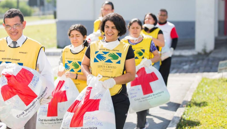 Voluntários carregando sacolas da cruz vermelha.