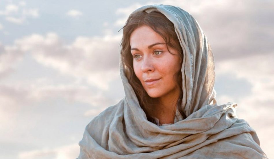 Maria mãe de Jesus com seu manto na cabeça pensativa olhando para o horizonte.