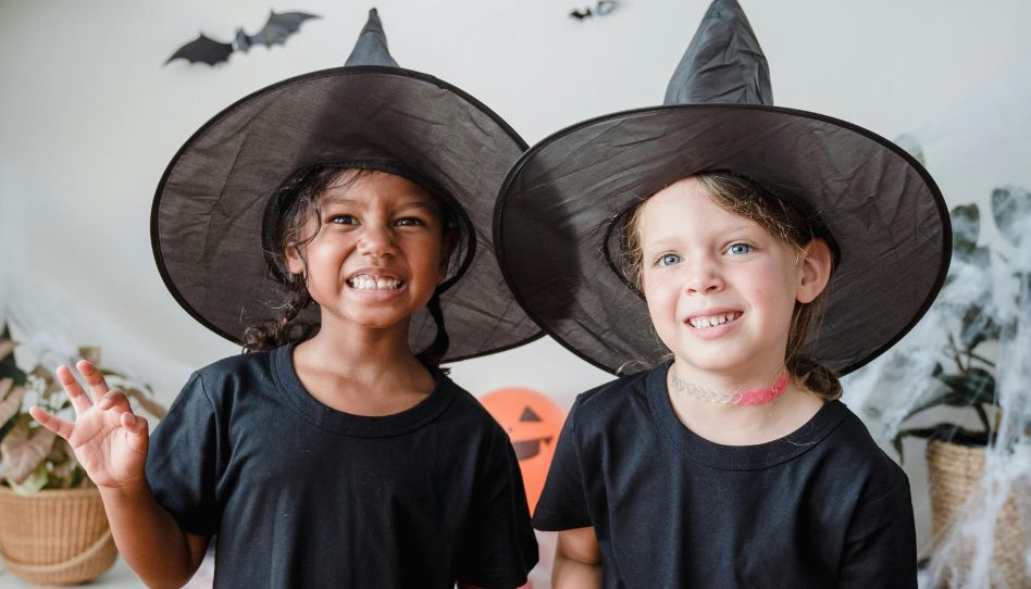 Meninas comchapeis de bruxa em uma sala decorada para o Halloween