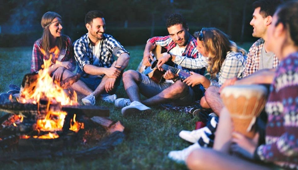 Amigos felizes em volta de uma fogueira.