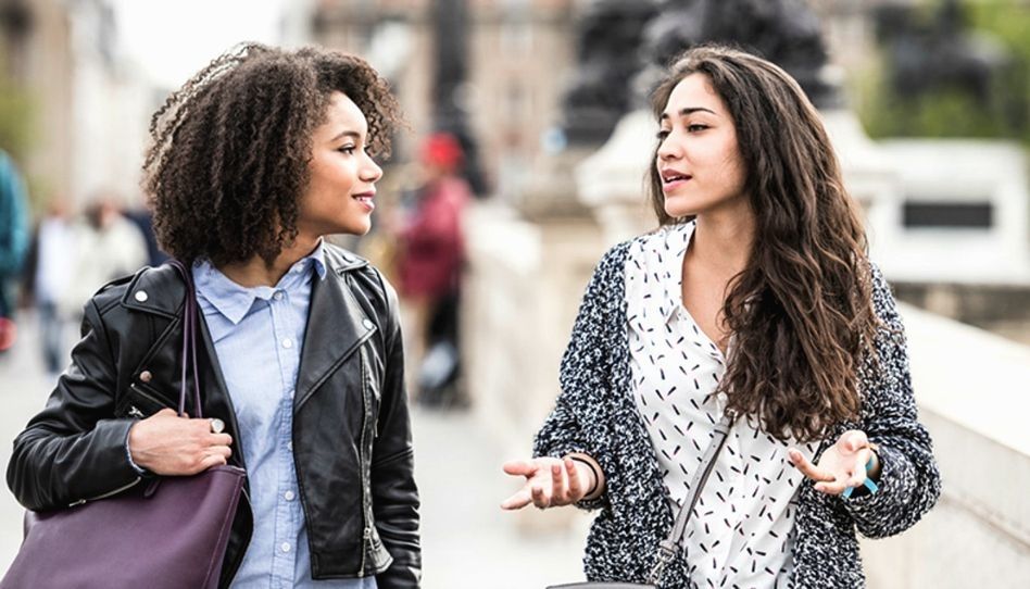 Duas mulheres andando na rua conversando. 