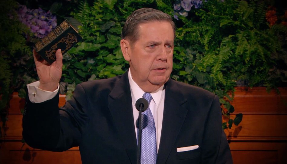 Close no púlpito mostrando as escrituras abertas enquanto Elder Jeffrey R. Holland cita o Livro de Mórmon com fervor.